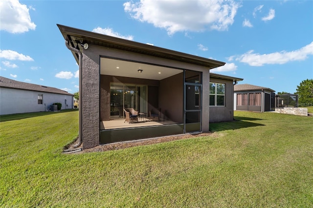 rear view of property featuring a patio area, a lawn, and a sunroom