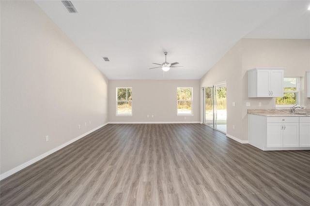 unfurnished living room with ceiling fan, sink, wood-type flooring, and vaulted ceiling