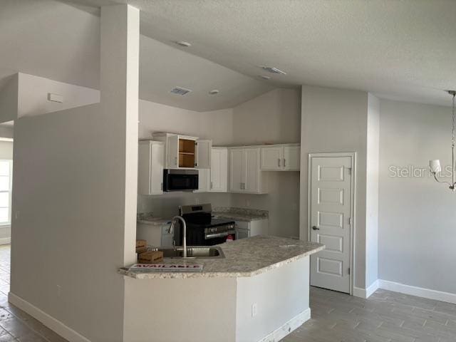 kitchen featuring kitchen peninsula, white cabinets, appliances with stainless steel finishes, a notable chandelier, and sink