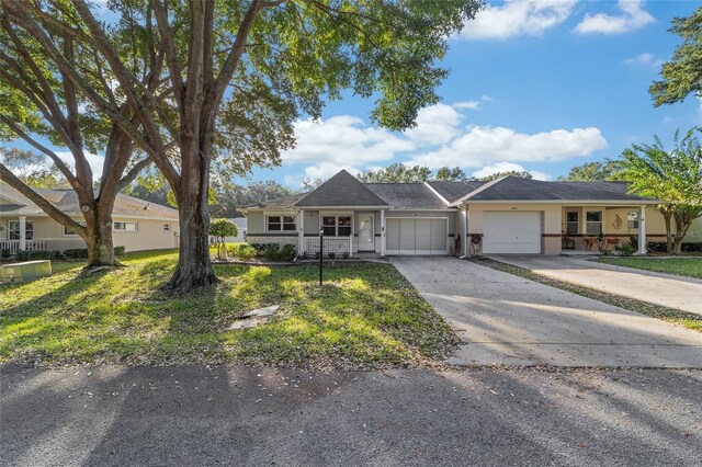 single story home featuring a porch, a front lawn, and a garage