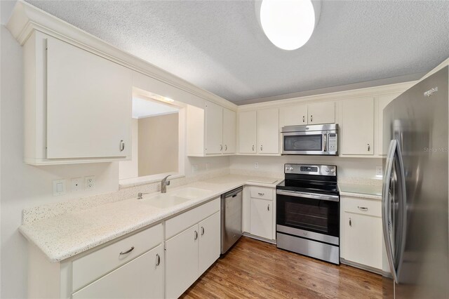 kitchen featuring sink, stainless steel appliances, a textured ceiling, and hardwood / wood-style flooring