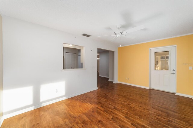 spare room with dark wood-type flooring, crown molding, and ceiling fan