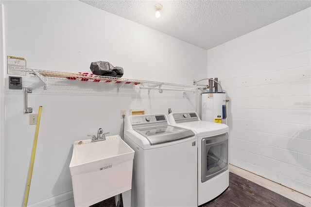 washroom featuring sink, independent washer and dryer, a textured ceiling, dark hardwood / wood-style flooring, and electric water heater