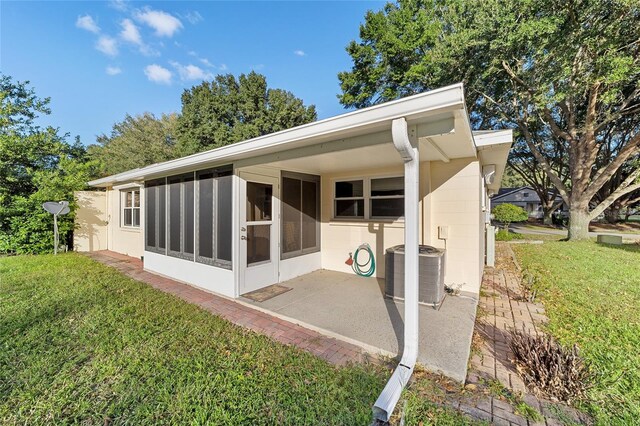 rear view of house with a patio, cooling unit, a yard, and a sunroom