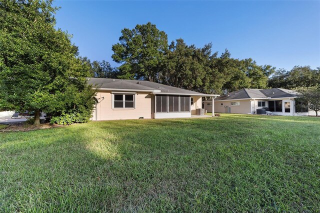 rear view of property featuring a yard and a sunroom