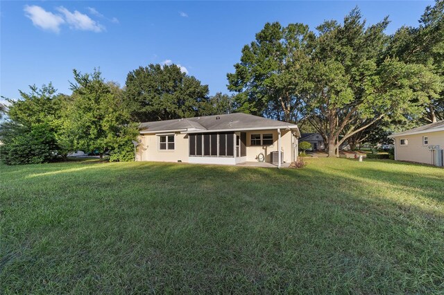 rear view of house featuring a sunroom, a lawn, and central AC unit