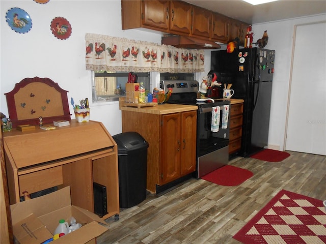 kitchen featuring stainless steel electric range, black fridge, and dark hardwood / wood-style floors