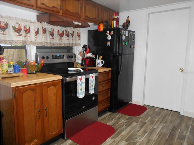 kitchen with dark hardwood / wood-style flooring, black fridge, and stainless steel electric range oven