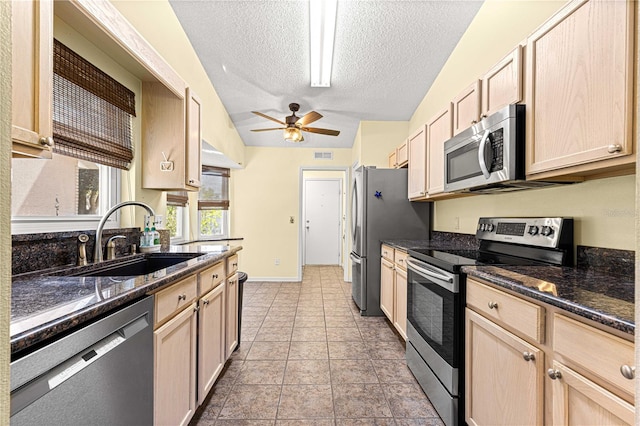 kitchen with lofted ceiling, a textured ceiling, light brown cabinetry, sink, and stainless steel appliances