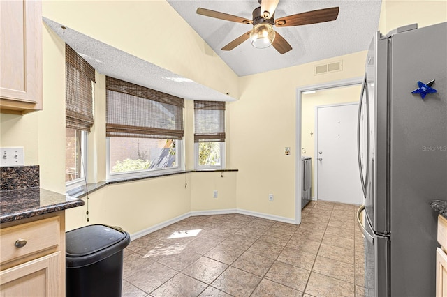 kitchen featuring light brown cabinetry, stainless steel fridge, a textured ceiling, and a healthy amount of sunlight