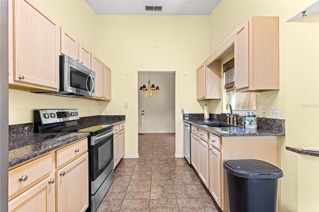 kitchen with appliances with stainless steel finishes, light tile patterned flooring, sink, dark stone counters, and light brown cabinets