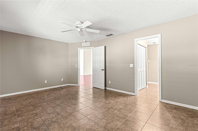 tiled spare room with a textured ceiling and ceiling fan