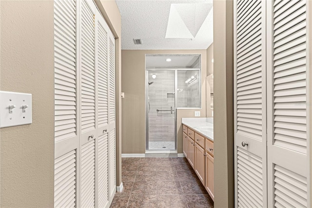 bathroom featuring vanity, a textured ceiling, a skylight, and an enclosed shower