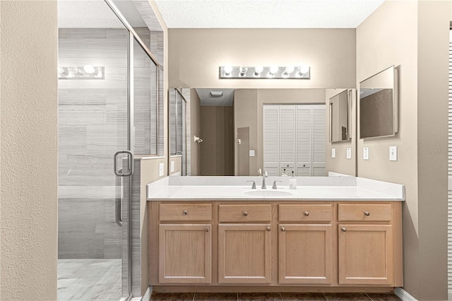 bathroom featuring a shower with door, vanity, and a textured ceiling