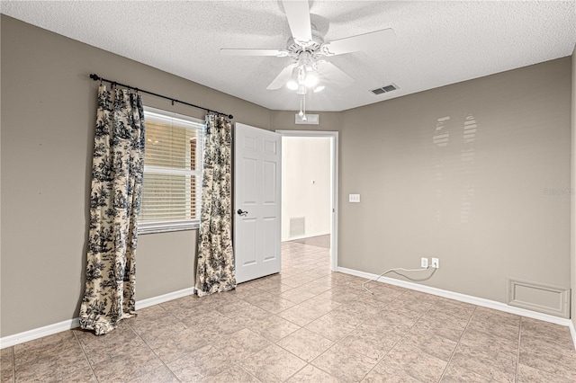 tiled empty room with a textured ceiling and ceiling fan