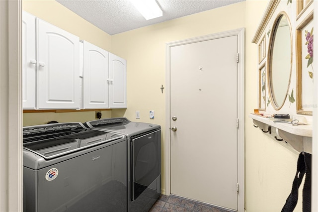 washroom with cabinets, a textured ceiling, and washing machine and clothes dryer