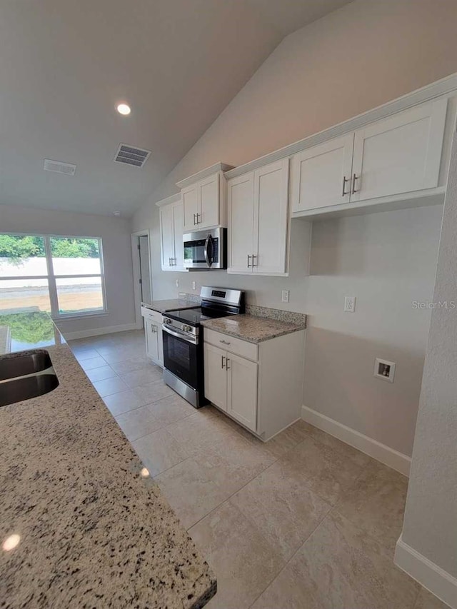 kitchen featuring lofted ceiling, white cabinets, light stone countertops, and stainless steel appliances