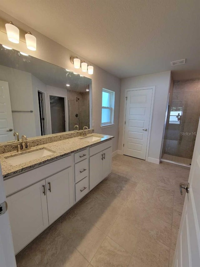 bathroom featuring vanity, an enclosed shower, and a textured ceiling