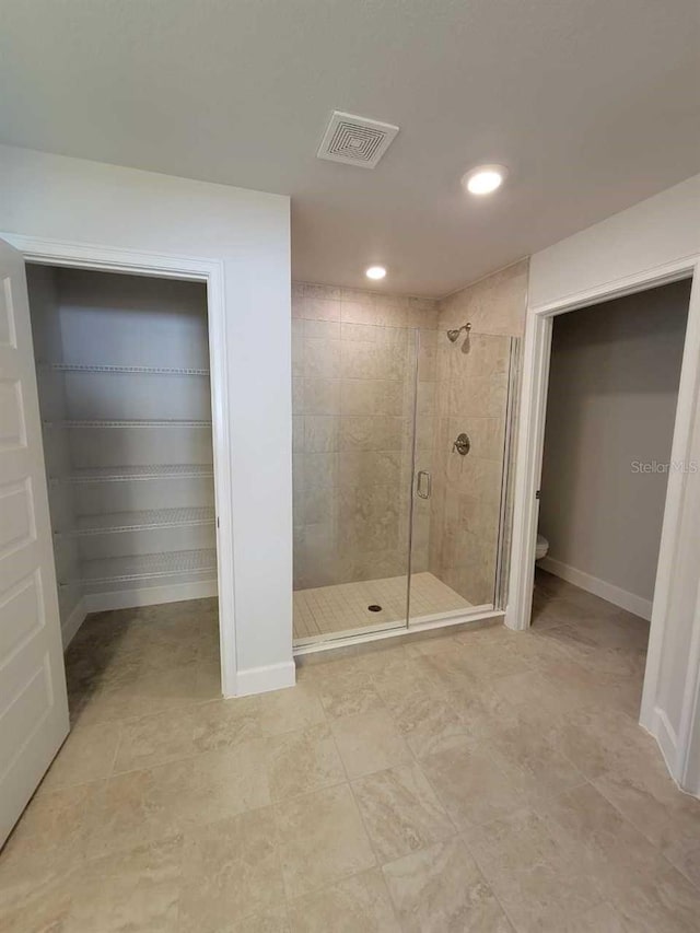 bathroom with a shower with door, toilet, and tile patterned floors