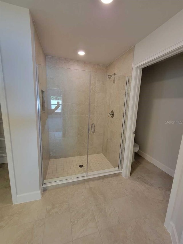 bathroom with toilet, a shower with shower door, and tile patterned floors