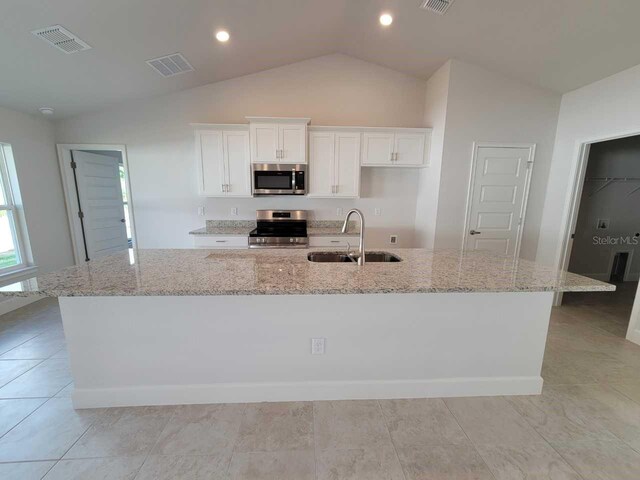 5892 SW 82nd Ln, Ocala, FL 34476 - kitchen featuring stainless steel appliances, a sink, vaulted ceiling, a spacious island, and white cabinets