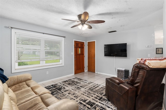 living room featuring ceiling fan, a textured ceiling, and light tile patterned floors