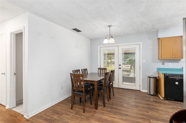 dining area featuring a textured ceiling, dark hardwood / wood-style floors, an inviting chandelier, and french doors