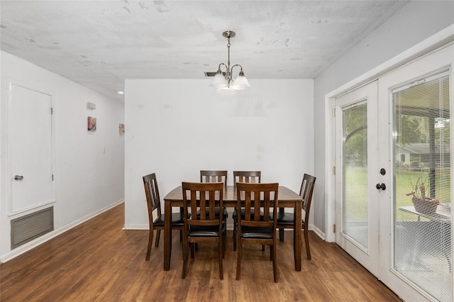 dining room with french doors, a textured ceiling, an inviting chandelier, and dark hardwood / wood-style flooring