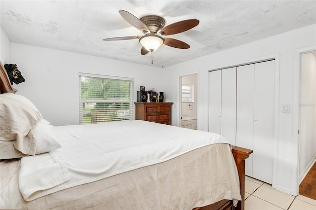 bedroom featuring ensuite bath, a textured ceiling, a closet, ceiling fan, and light tile patterned floors