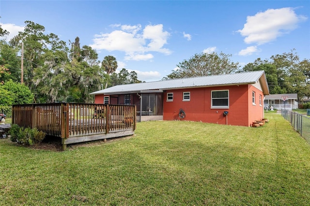 back of house featuring a wooden deck, a yard, and a sunroom