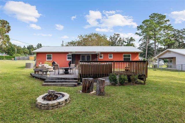 rear view of property featuring a wooden deck, an outdoor fire pit, central air condition unit, and a lawn