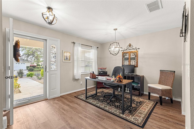 office with hardwood / wood-style floors, a textured ceiling, a wealth of natural light, and an inviting chandelier