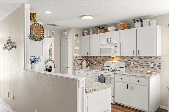 kitchen featuring kitchen peninsula, stove, sink, hardwood / wood-style flooring, and white cabinetry