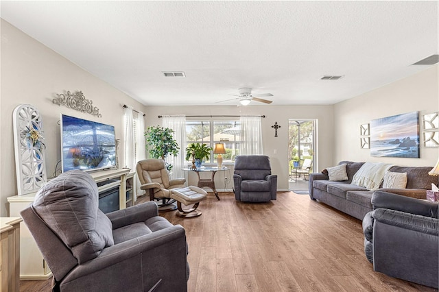 living room featuring ceiling fan, hardwood / wood-style floors, and a textured ceiling