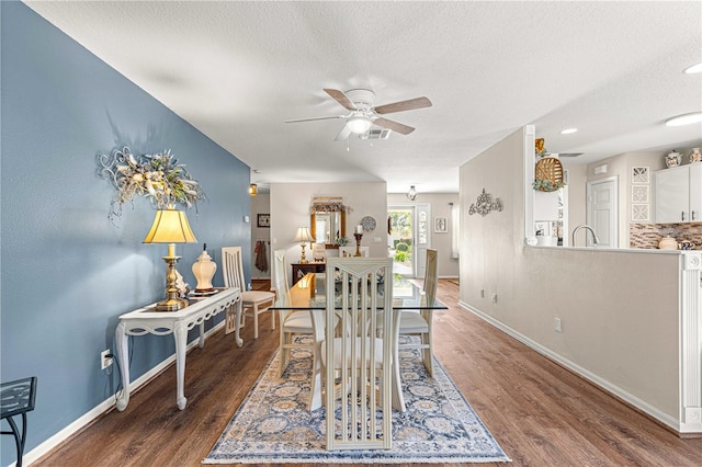 dining space featuring ceiling fan, dark wood-type flooring, and a textured ceiling