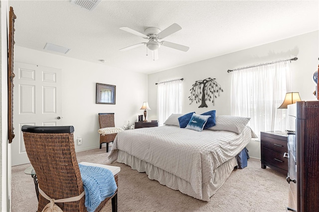 bedroom with a textured ceiling, ceiling fan, and light carpet