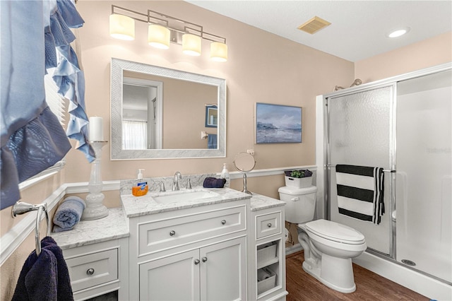 bathroom featuring vanity, wood-type flooring, an enclosed shower, and toilet