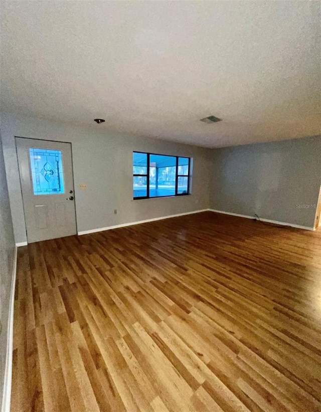 unfurnished living room featuring a textured ceiling and wood-type flooring