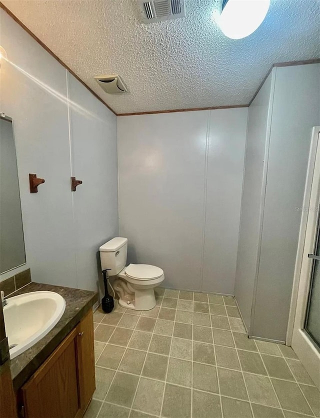 bathroom featuring a textured ceiling, toilet, tile patterned floors, walk in shower, and vanity