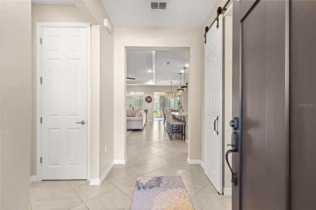 hall featuring a barn door and light tile patterned flooring