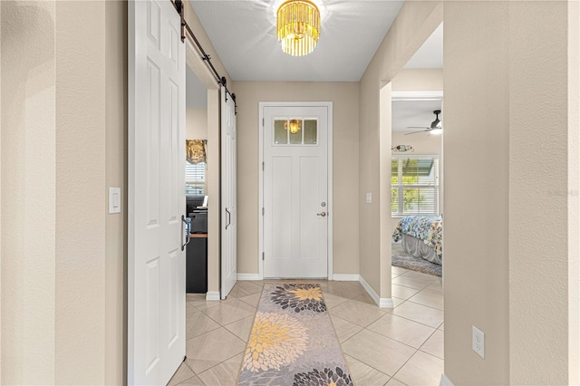 tiled foyer entrance with ceiling fan and a barn door