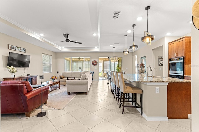 kitchen with light stone countertops, stainless steel double oven, ceiling fan, decorative light fixtures, and light tile patterned floors