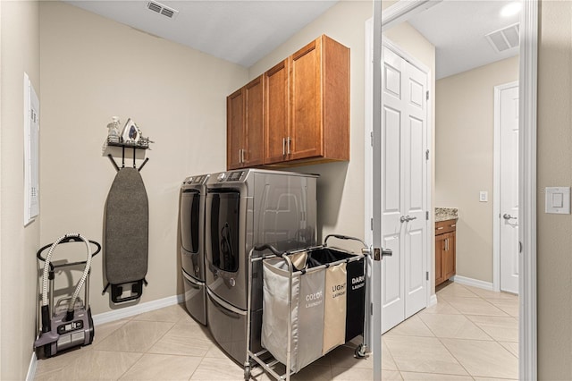 washroom featuring cabinets, washer and clothes dryer, and light tile patterned floors