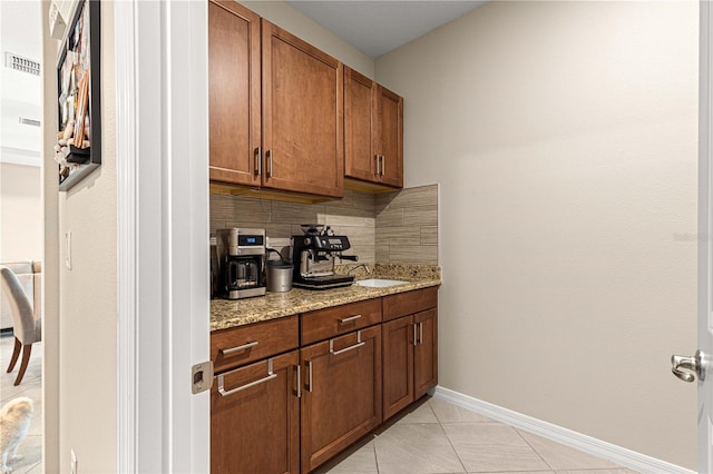 bar featuring tasteful backsplash, light stone countertops, and light tile patterned floors