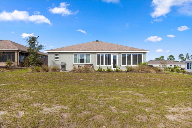 rear view of property featuring a sunroom and a lawn