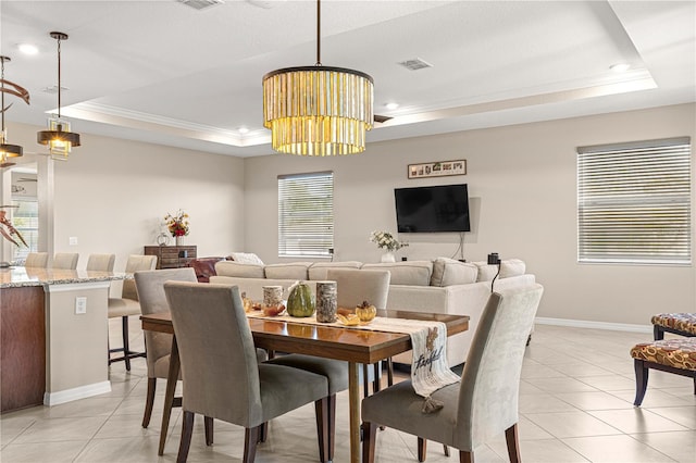 tiled dining room featuring crown molding and a raised ceiling