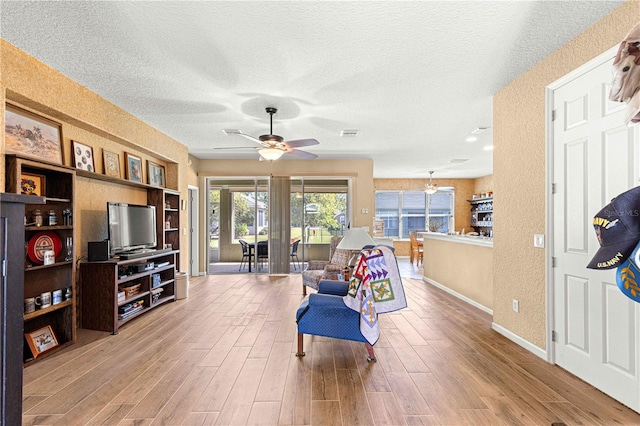 living area featuring hardwood / wood-style floors, a textured ceiling, and ceiling fan