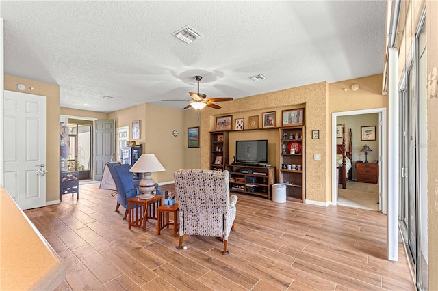 living room featuring a textured ceiling, light hardwood / wood-style floors, and ceiling fan