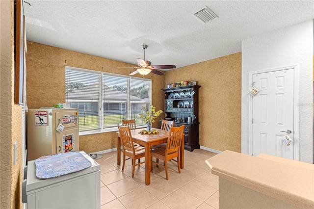 tiled dining space featuring a textured ceiling and ceiling fan