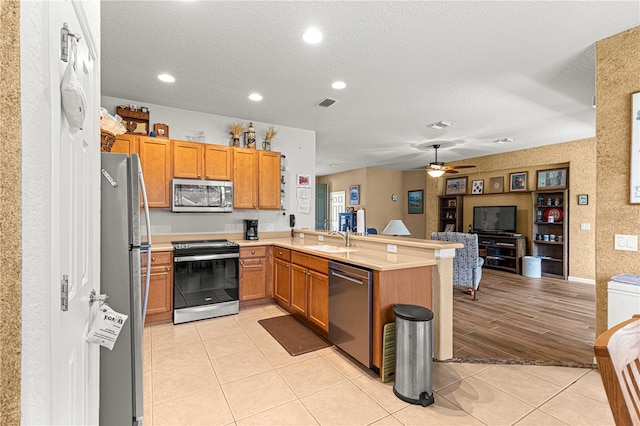 kitchen featuring kitchen peninsula, ceiling fan, sink, light hardwood / wood-style floors, and stainless steel appliances